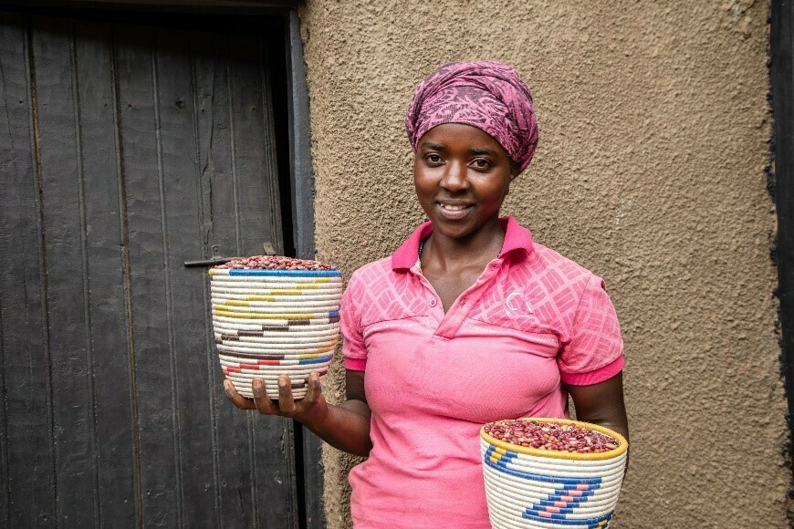 Alice stands in front of her home in Rwanda.