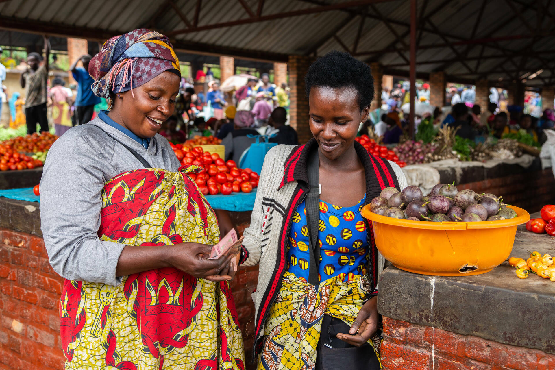 Diane, a smallholder farmer in Rwanda, with a customer in her local market. With support from OI AgFinance’s GROW program, Diane has grown her income and farm to provide for her three children by strengthening her small business management skills, building savings habits, and increasing her income with market sales. 