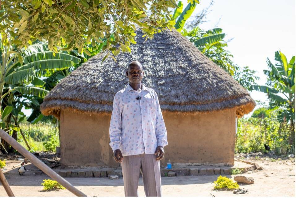 John stands in front of his home.